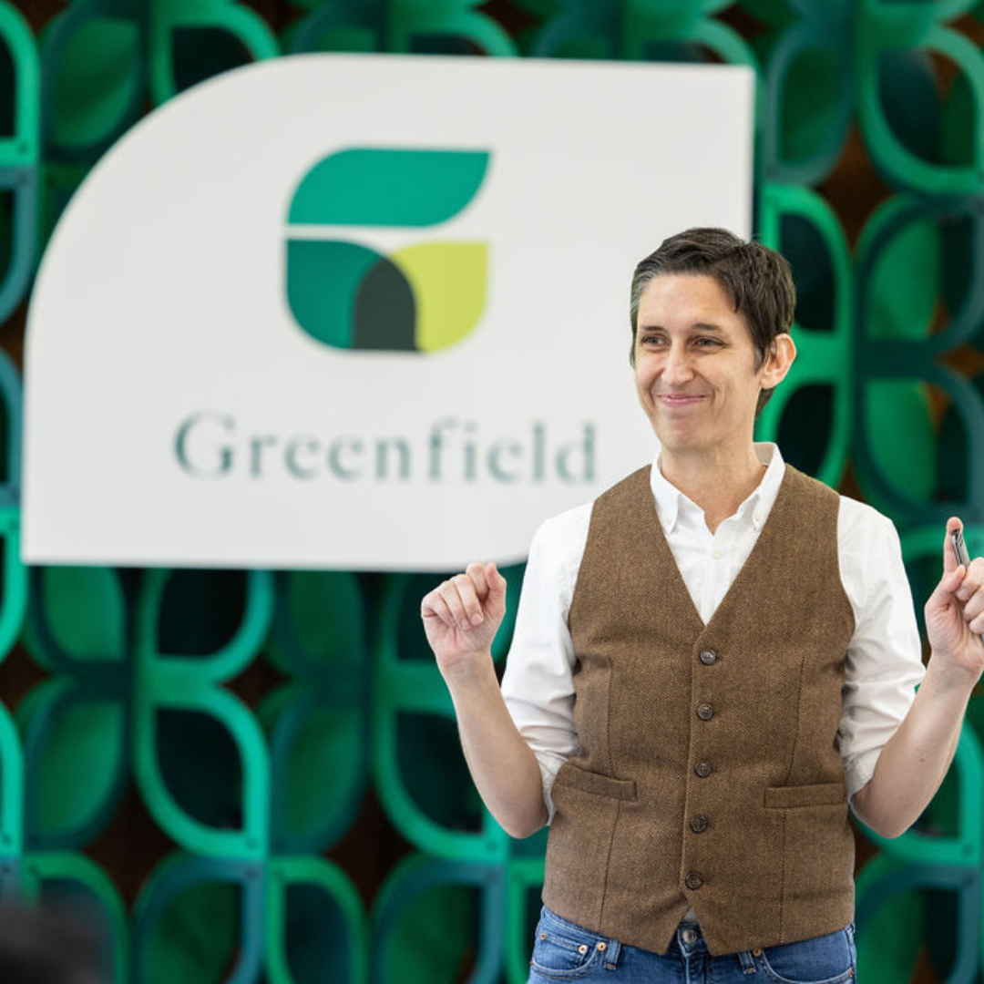 Photo of instructor smiling in front of Greenfield sign.